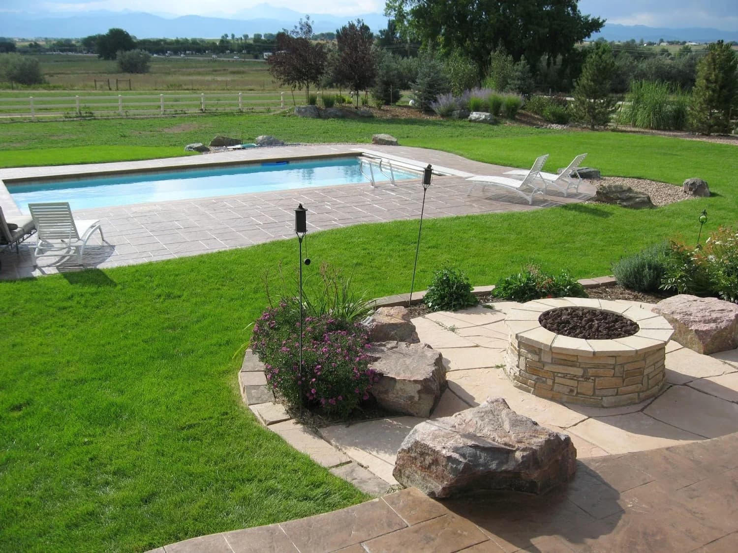 Backyard pool, firepit, and manicured lawn by J&P Landscaping
